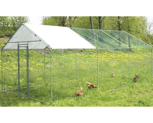 Venkovní výběh se sítí a několika kuřaty na louce.