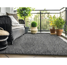 Balkónová scéna s ratanovou pohovkou, rostlinami a šedým umělým trávníkem