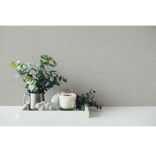 Dekorativní zátiší scéna s texturovaným pozadím, skládající se ze svíčky, ozdoby a rostliny.