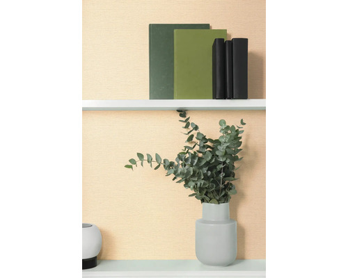 Dekorativní police s knihami a eukalyptem ve váze.