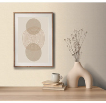 Dekorativní obrázek s kruhovým vzorem v dřevěném rámu, na stole s ozdobnou vázou a knihami