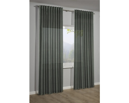 Dva závěsy před oknem s výhledem do přírody.