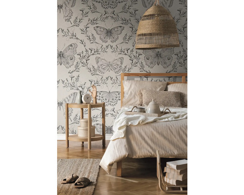 Ložnice s postelí, nočním stolkem, lampou a tapetou s motýlím vzorem