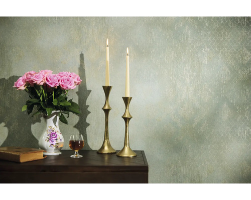 Dekorativní aranžmá s růžemi, svíčkami a starožitnými prvky na stole před vzorovanou zdí