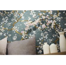 Detailní záběr stěny s květinovou tapetou, polštáři a dekorativními vázami.