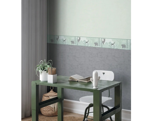 Dekorativní dětský pokoj se stolem, židlí a bordurou tapety s motivem lesa.