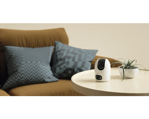 Kamera Imou na stole vedle pokojové rostliny a pohovky