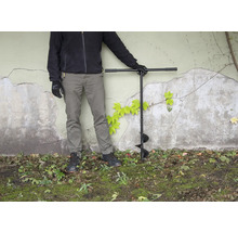 Osoba se zemním vrtákem na zahradě