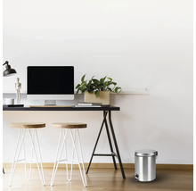 Scéna se stolem, stoličkami a kovovým odpadkovým košem s pedálem