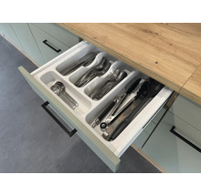 Otevřená kuchyňská zásuvka s vložkou na příbory a různými kusy příborů.