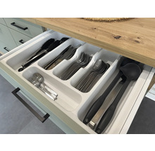 Otevřená zásuvka s vložkou na příbory a různým kuchyňským náčiním, jako jsou kleště, nože, vidličky, lžíce a naběračky.