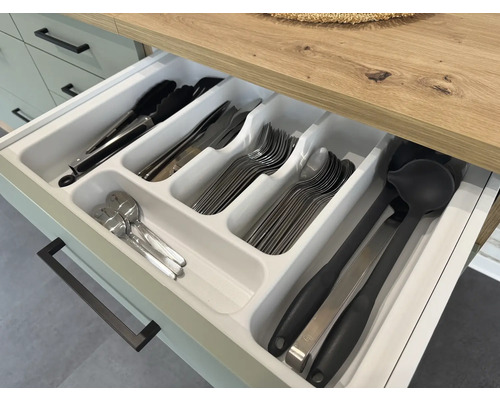Otevřená zásuvka s vložkou na příbory a různým kuchyňským náčiním, jako jsou kleště, nože, vidličky, lžíce a naběračky.