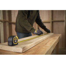 Řemeslník měří dřevěnou desku svinovacím metrem Stanley Fatmax, délka 5 metrů.