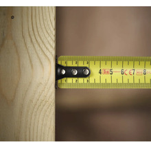 Žlutý svinovací metr měří kus dřeva