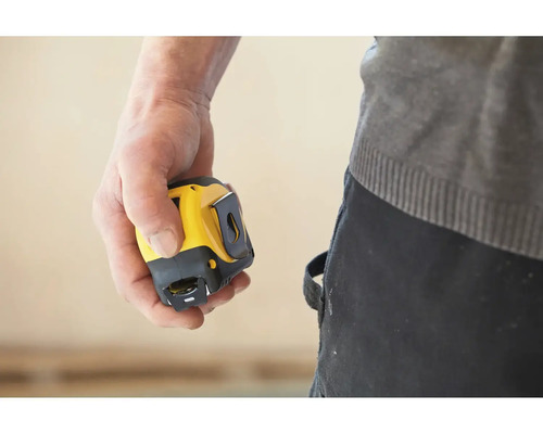 Ruka drží žlutý a černý svinovací metr.