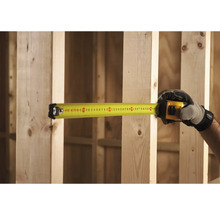 Žlutý svinovací metr měří dřevěné trámy