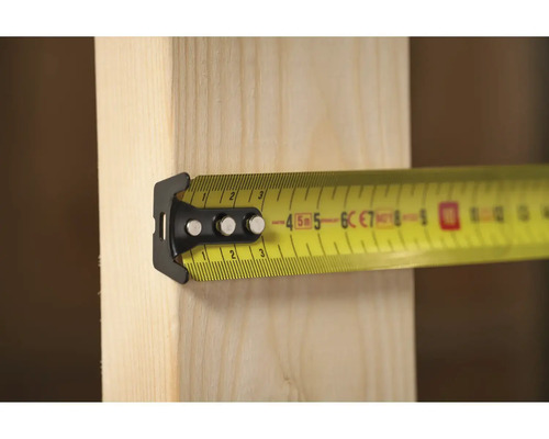 Žlutý svinovací metr na dřevěné desce