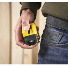 Osoba drží žlutý svinovací metr s klipem na opasek.