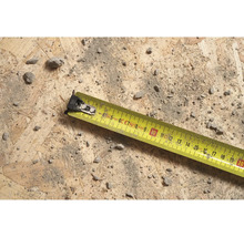 Žlutý svinovací metr na dřevěném povrchu se špínou