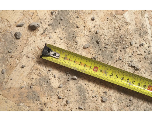 Žlutý svinovací metr na dřevěném povrchu se špínou