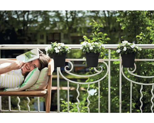 Žena relaxuje s knihou na lavičce na balkoně s truhlíky