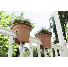 Dva květináče visí na zábradlí s květinami.