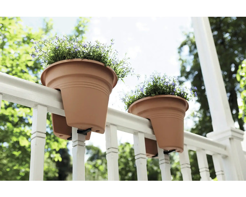 Dva květináče visí na zábradlí s květinami.