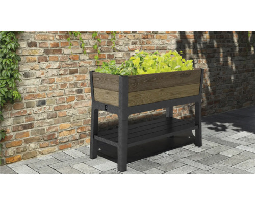 Vyvýšený záhon s úložným prostorem a rostlinami před cihlovou zdí