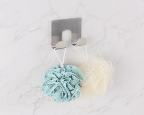 Pohled shora na nerezový háček na ručníky s koupelnovými houbami na mramorové stěně