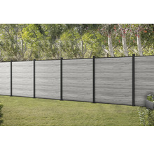 Šedý dřevěný plot s černými sloupky v zahradě.