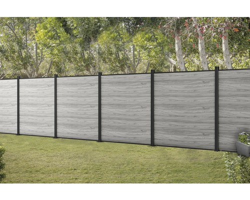 Šedý dřevěný plot s černými sloupky v zahradě.