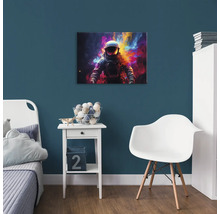 Dekorativní dětský pokoj s obrázkem astronauta na modré stěně nad nočním stolkem.