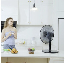 Stolní ventilátor ve světlé kuchyni se ženou držící šálek