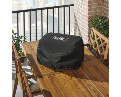 Černý ochranný kryt na gril Weber na dřevěném stole