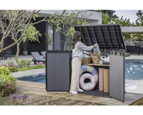 Snímek ženy používající venkovní úložný box na dřevěné terase u bazénu k ukládání věcí