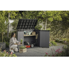 Žena sází květiny před otevřenou zahradní skříní se zahradním nářadím