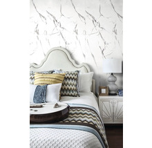 Ložnice s postelí, nočním stolkem a tapetou s mramorovým vzorem