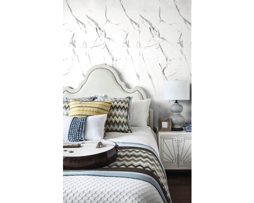Ložnice s postelí, nočním stolkem a tapetou s mramorovým vzorem