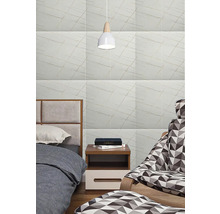 Ložnice s obkladem stěn ve vzhledu mramoru, postelí, nočním stolkem a lampou