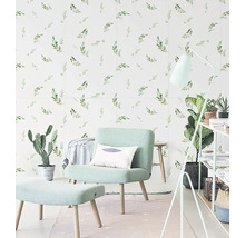 Světlá místnost s křeslem, stoličkou, stojací lampou a obkladačkami se vzorem listů