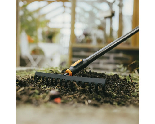 Zahradní hrábě používané na záhoně se zeminou.