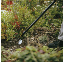 Zahradní motyka používaná na záhoně k úpravě půdy.