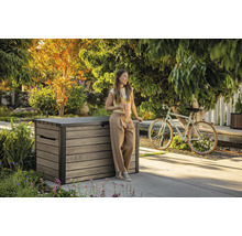 Zahradní scéna s ženou opírající se o dřevěný úložný box a držící šálek kávy.