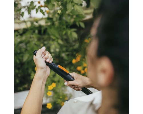 Osoba drží v ruce trysku zahradní hadice