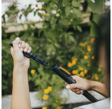 Osoba připojuje zahradní nářadí pro zavlažování zahrady