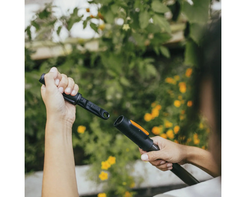 Osoba připojuje zahradní nářadí pro zavlažování zahrady