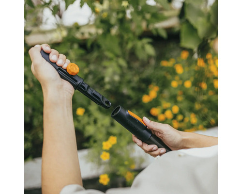 Dvě ruce spojují zavlažovací systém Fiskars.