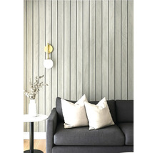 Obývací pokoj s šedou pohovkou, polštáři a tapetou se vzorem pruhů