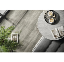 Interiérová fotografie místnosti s dřevěnou podlahou, kulatým stolem s mramorovou deskou a dekoracemi.