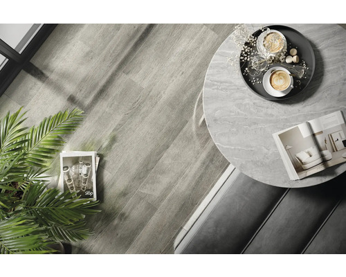 Interiérová fotografie místnosti s dřevěnou podlahou, kulatým stolem s mramorovou deskou a dekoracemi.